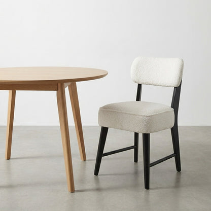 Round wooden table with a cushioned chair on a gray floor.