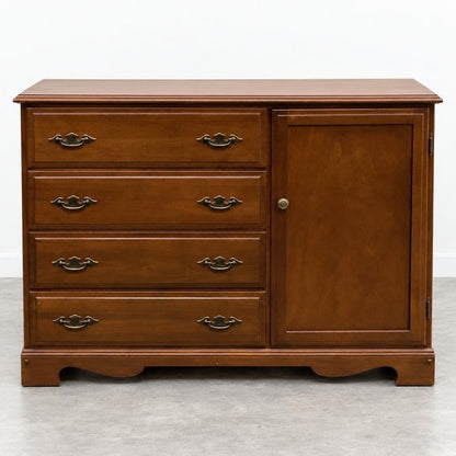 Wooden dresser with four drawers and a cabinet on a gray floor.