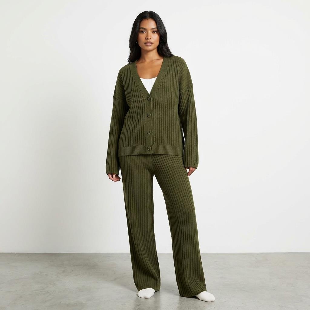Person in green ribbed knit outfit standing against a plain background.