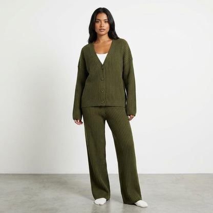 Person in green ribbed knit outfit standing against a plain background.