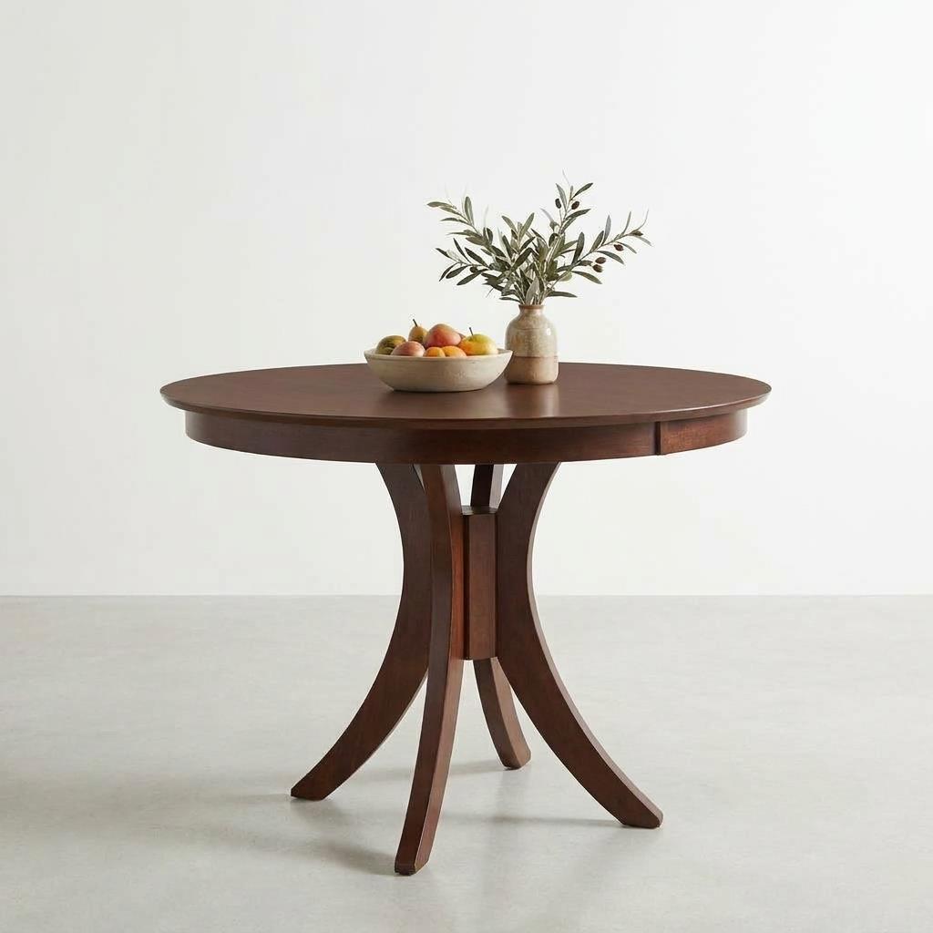 Round wooden table with fruit bowl and vase of greenery.