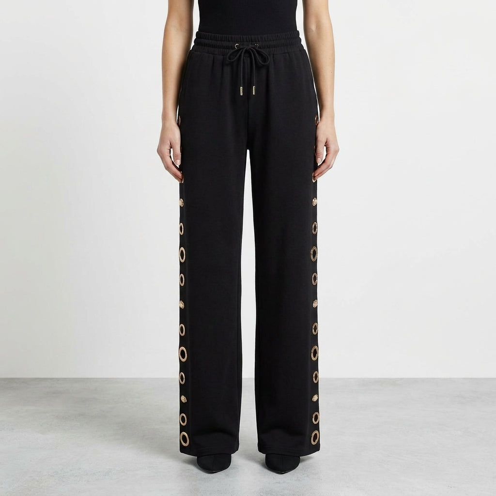 Black pants with drawstring and gold ring accents on the sides.