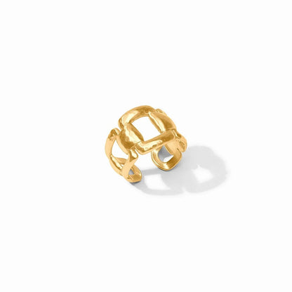 A sculptural gold ring with an interwoven design rests on a white surface.
