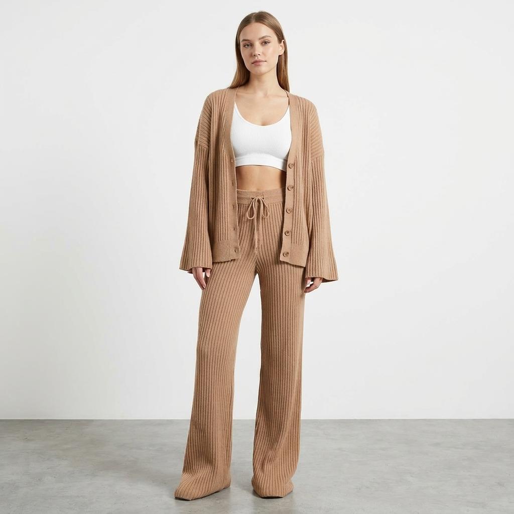 Woman in beige knit outfit with white crop top, standing on a gray floor.