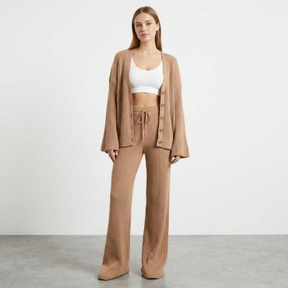 Woman in beige knit outfit with white crop top, standing on a gray floor.