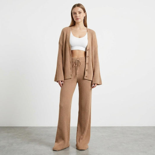 Woman in beige knit outfit with white crop top, standing on a gray floor.