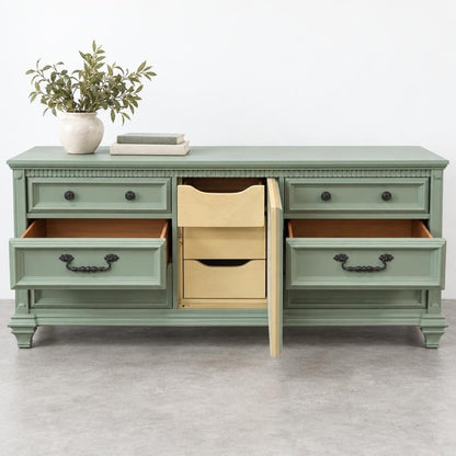 Green vintage dresser with open drawers and a vase of leaves on top.