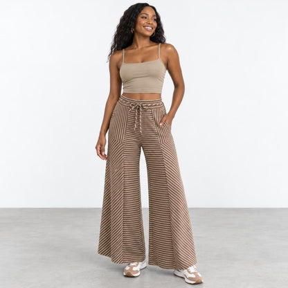 Smiling woman in striped wide-leg pants and a beige crop top, standing casually.