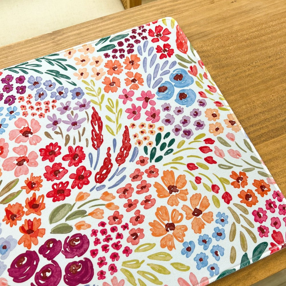 Colorful floral pattern on a rectangular mat over a wooden surface.