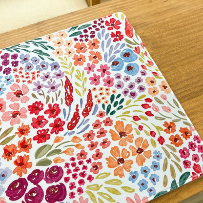 Colorful floral pattern on a rectangular mat over a wooden surface.