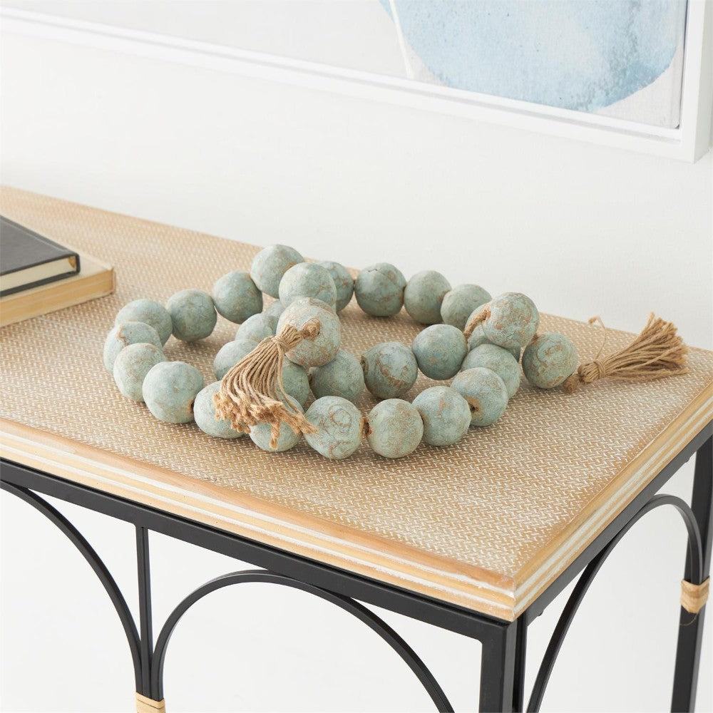 Wooden bead garland with tassels on a table.