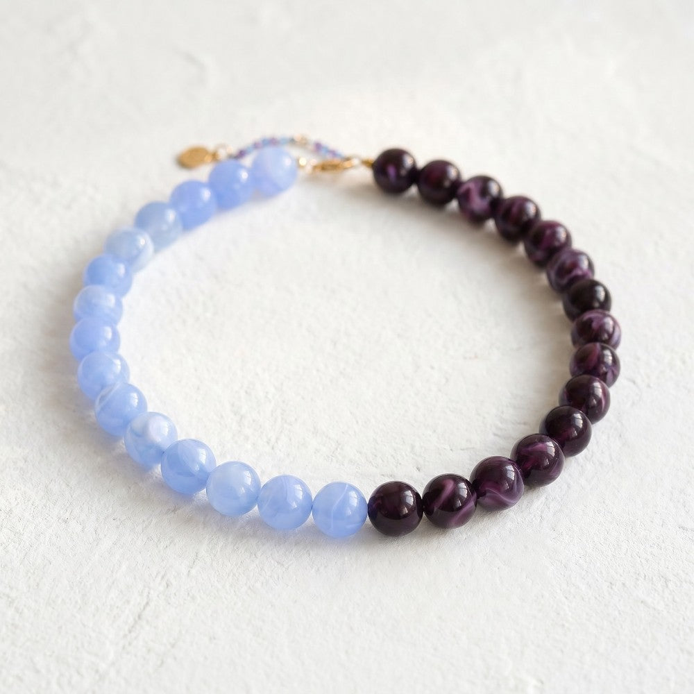 Beaded bracelet with blue and purple stones on a light background.