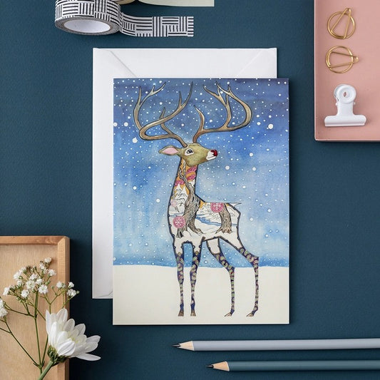 Festive reindeer card with decorative accents on a teal desk.