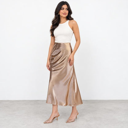 Woman modeling a white sleeveless top, champagne satin midi skirt, and embellished heels.