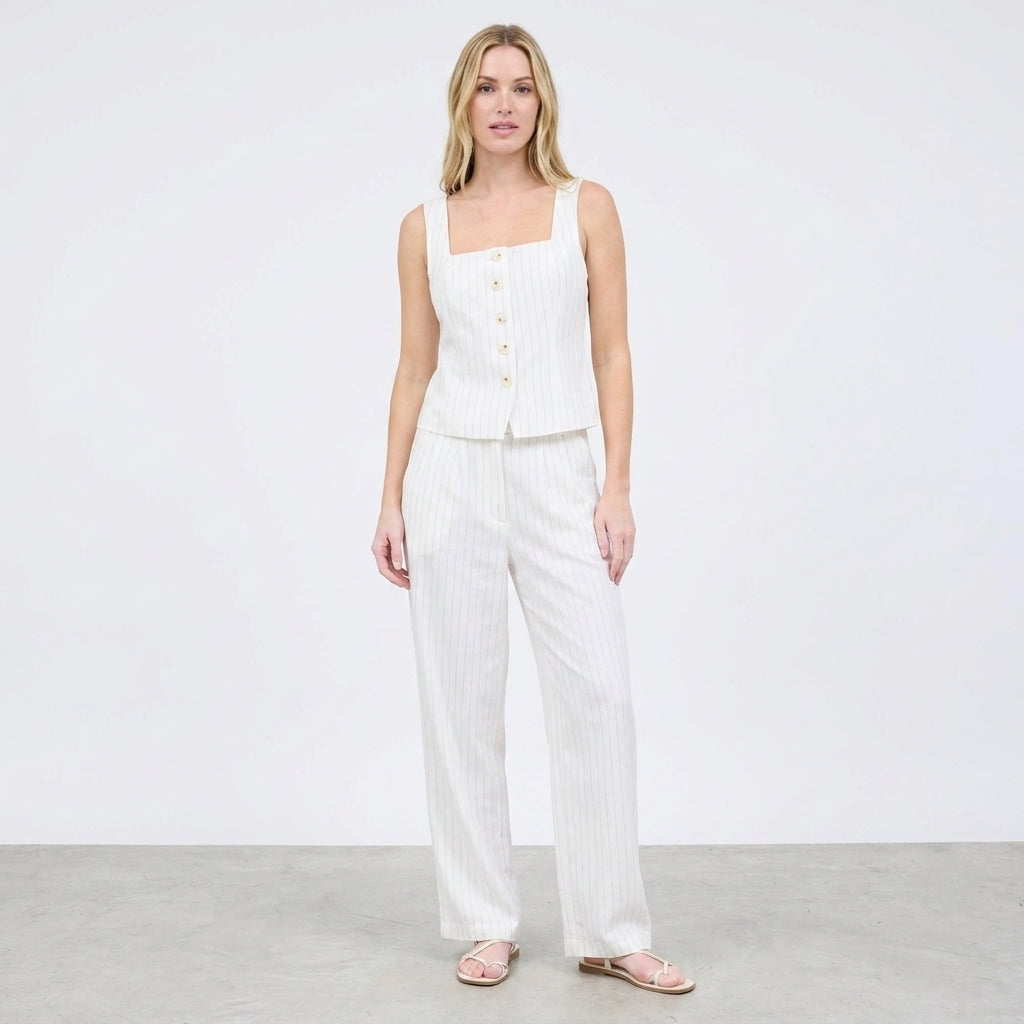 Woman in a white, buttoned top and pants ensemble.