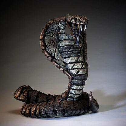 Stone cobra sculpture with fangs bared and coiled tail.