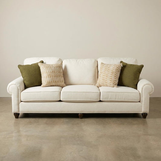Beige sofa with green and beige cushions on a plain background.