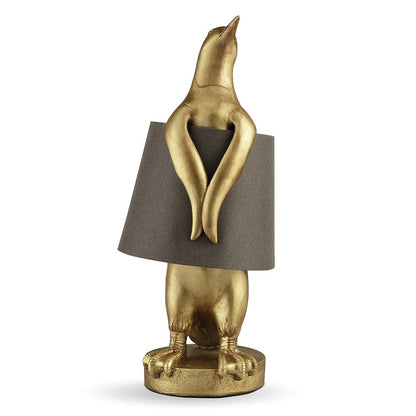 Gold penguin lamp with a grey lampshade.
