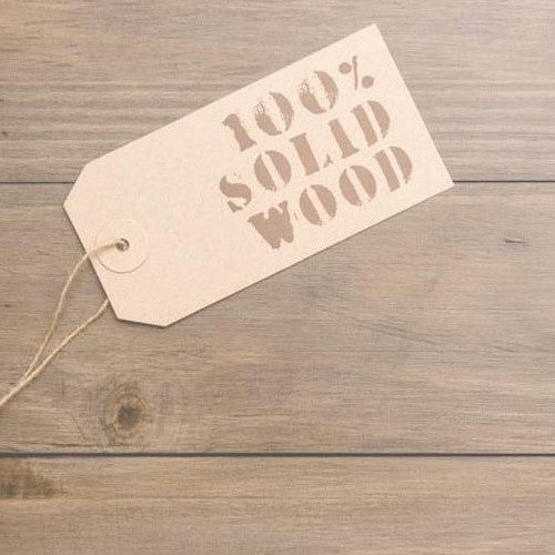 Label reading "100% Solid Wood" on a wooden surface.