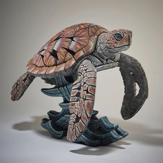Intricate sea turtle sculpture with textured shell on blue wave base.