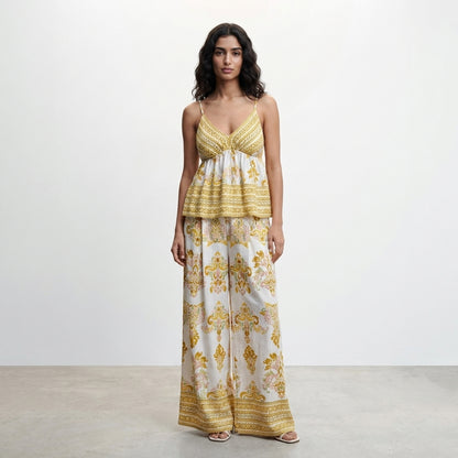 Woman in patterned yellow and white ensemble against a plain background.