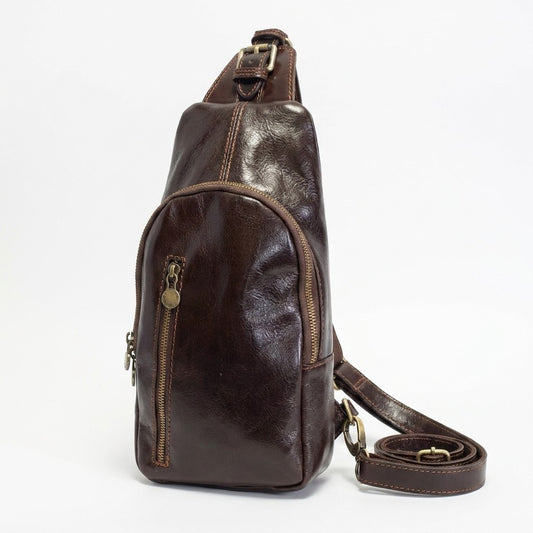 Brown leather sling bag with brass zippers.