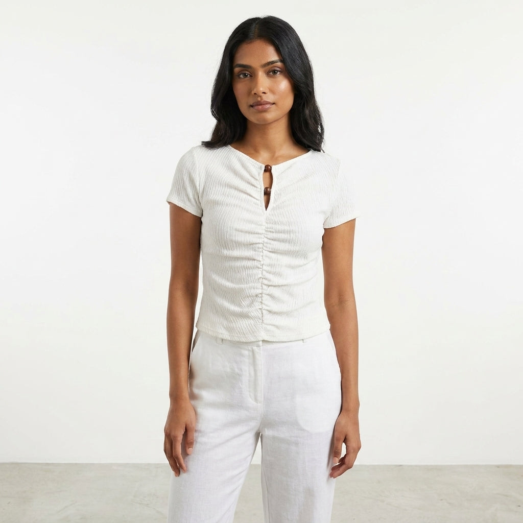 Person in a white outfit stands against a plain background.