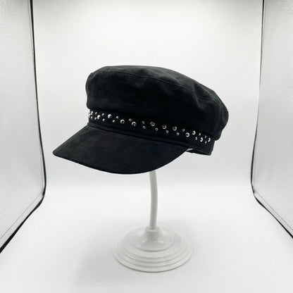 Black cap with studs on a stand in a lightbox setup.