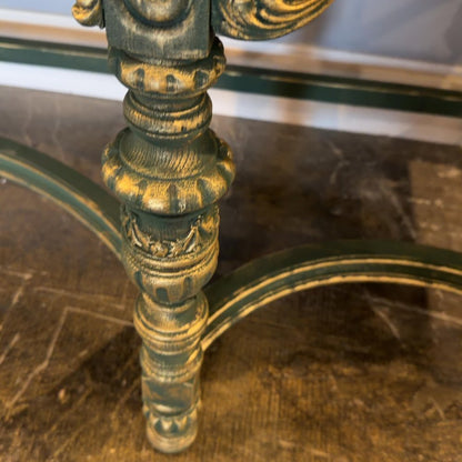 Close-up of an ornate, weathered gold-and-green metal table leg and curved support.