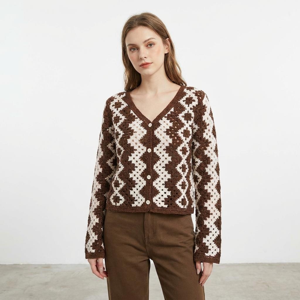 Woman in a patterned brown cardigan, neutral expression, standing against a plain background.
