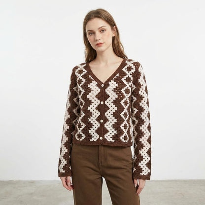 Woman in a patterned brown cardigan, neutral expression, standing against a plain background.