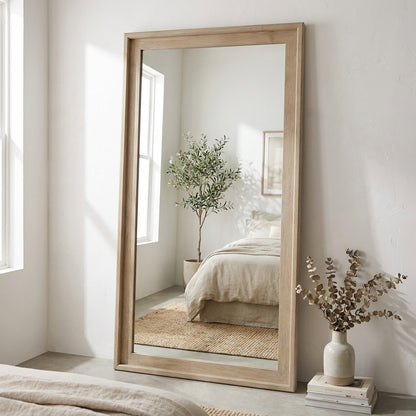 Minimalist bedroom mirror with a potted plant reflection and neutral decor.