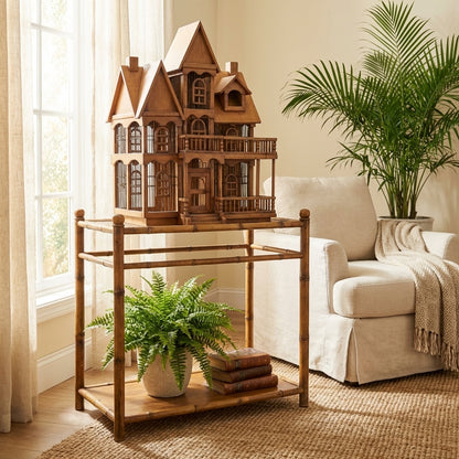Wooden dollhouse on table near chair and plant.