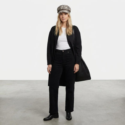 Woman in black outfit with leopard-print cap on a neutral background.