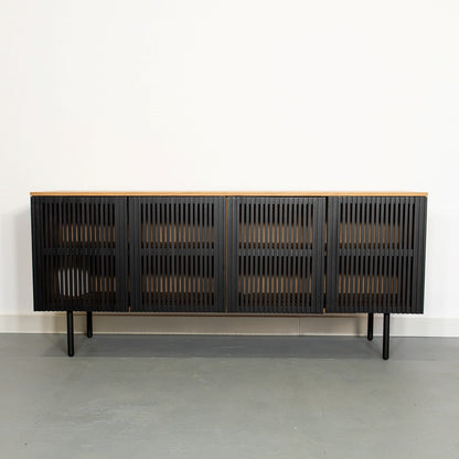 Black slatted sideboard with wooden top, standing against a white wall.