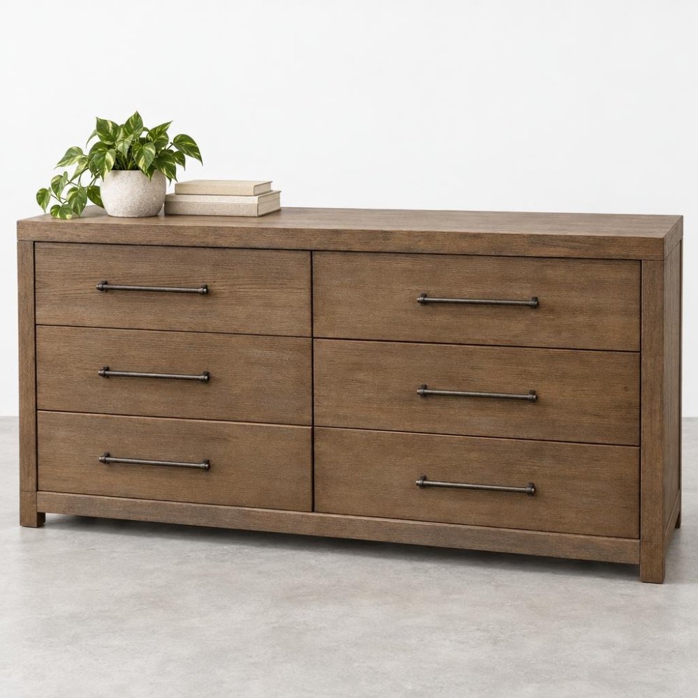 A wooden six-drawer dresser topped with a potted plant and books.