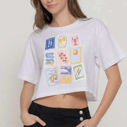 Woman in white crop top with colorful stamp designs.