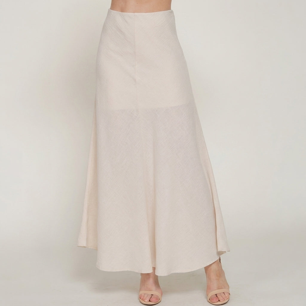 Woman modeling a flowy, cream-colored skirt and sandals.