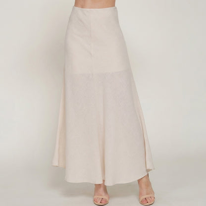 Woman modeling a flowy, cream-colored skirt and sandals.