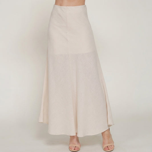 Woman modeling a flowy, cream-colored skirt and sandals.