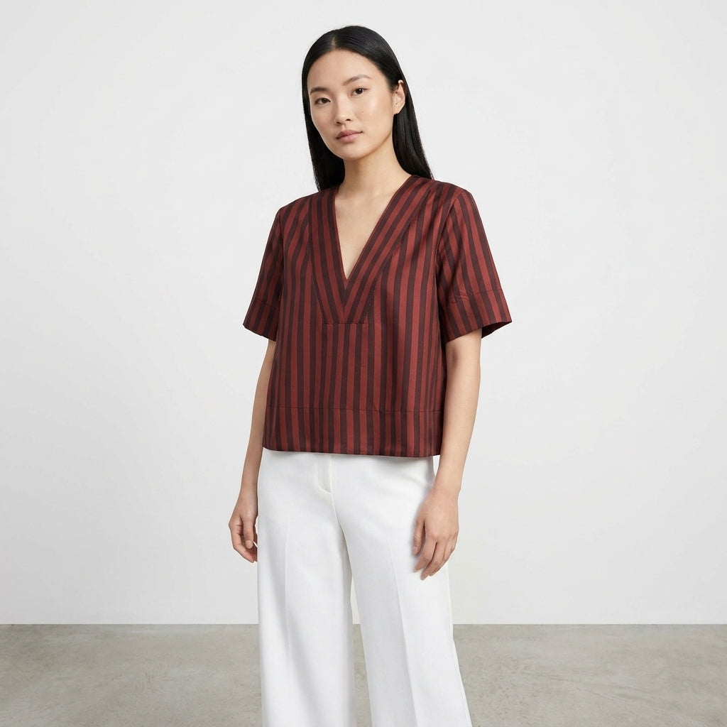 Person in a striped top and white pants standing against a plain background.