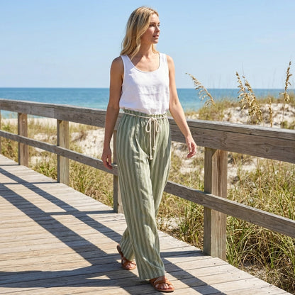 Woman walking on a wooden boardwalk by the sea on a sunny day.