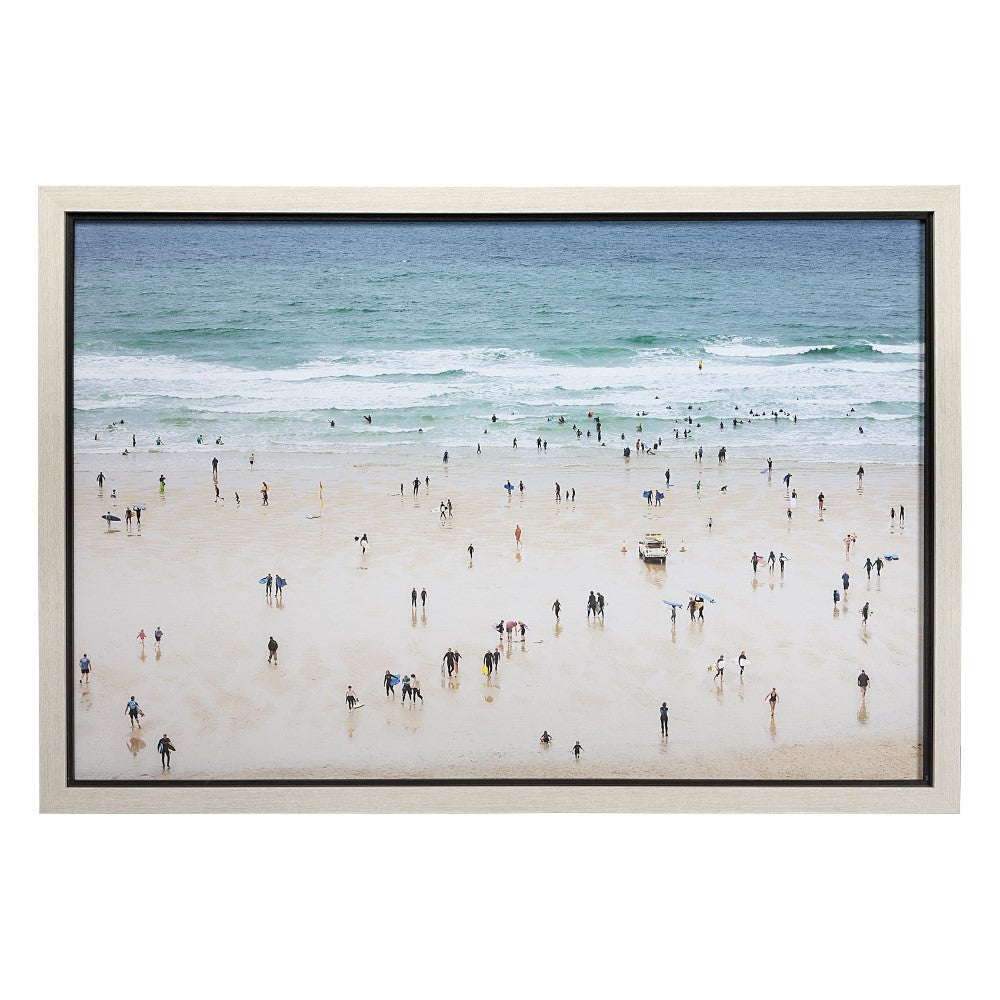 Crowded beach scene with people enjoying the ocean under a clear sky.