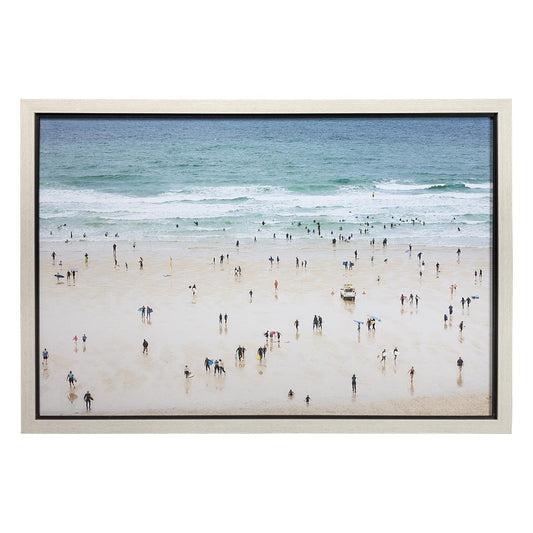 Crowded beach scene with people enjoying the ocean under a clear sky.