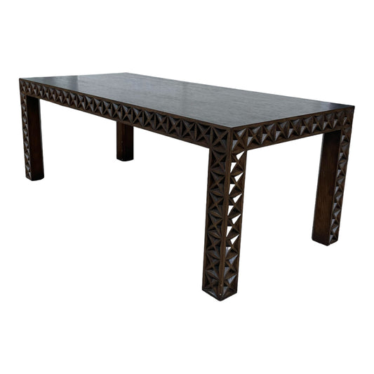 Wooden table with a geometric carved edge design.