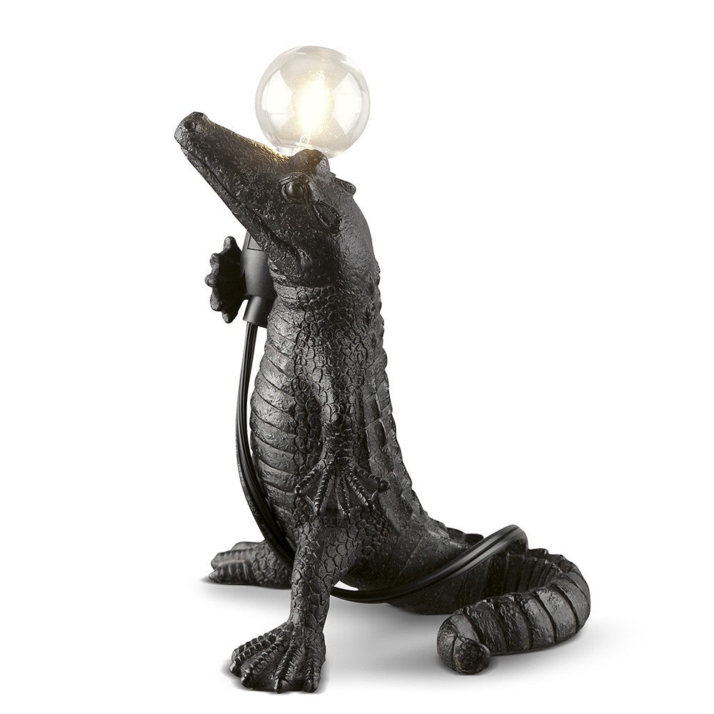 Crocodile-shaped lamp with a glowing bulb on its snout.