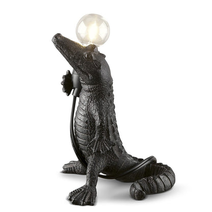 Crocodile-shaped lamp with a glowing bulb on its snout.