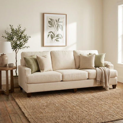 Cozy beige living room with a sofa, plants, and wall art.