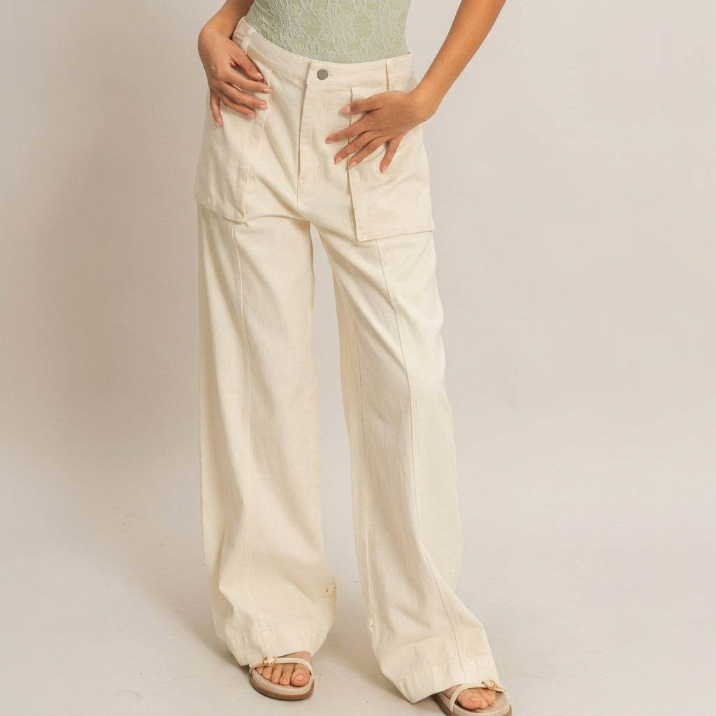 Woman wearing wide beige pants, green top, sandals; light background.