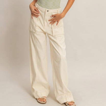 Woman wearing wide beige pants, green top, sandals; light background.